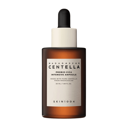 Ampolla facial marrón de SKIN1004, con etiqueta en tono crema, tapón dosificador negro y gotero.